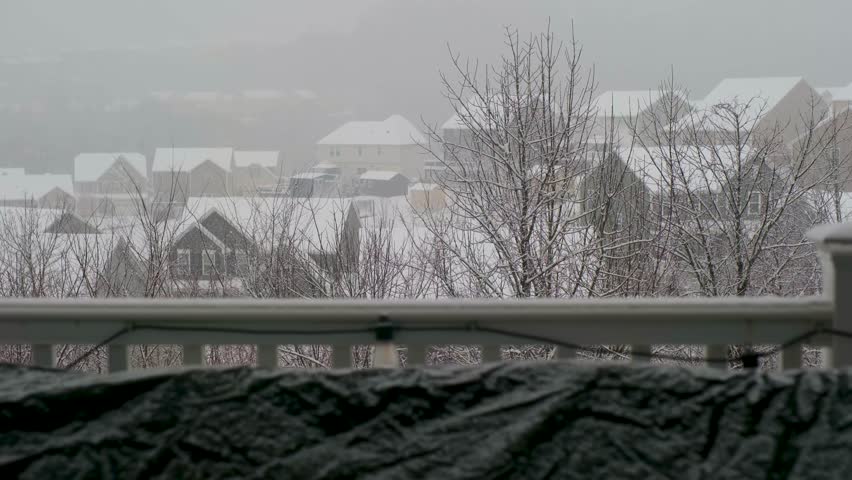 Snow covers houses and trees in a neighborhood during winter storm in a suburban area