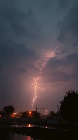 Storm clouds and lightning above the countryside, A bolt of lightning zags across the sky making the clouds glow and lighting the ground where water from the rain runs down a sandy wash in the desert 
