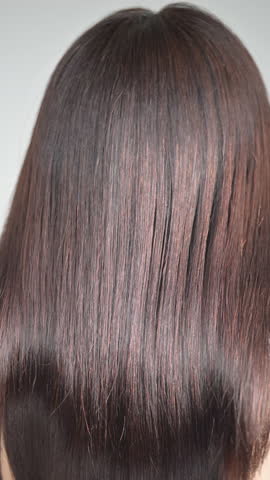 Close-up video of glossy, long black hair with beautiful, cuticle-smooth straight strands—evoking hair care imagery	