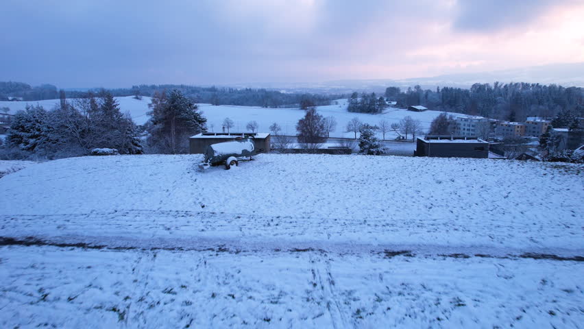 Aerial of a man sledding down a snowy hill at sunset, Uster, Switzerland
