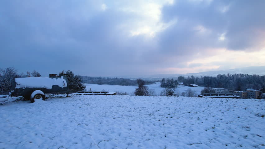 Aerial of a man with a wood sledge, standing on top of a snowy hill, Uster, Switzerland