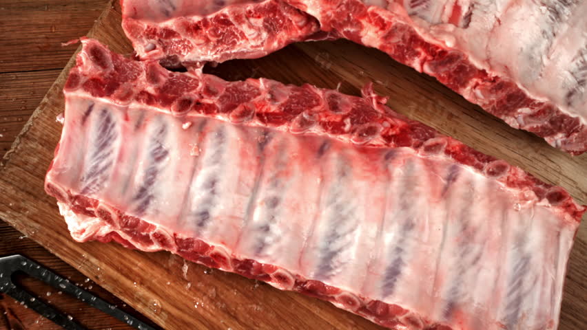 Raw pork ribs fall onto a cutting board. Filmed on a high-speed camera at 1000 fps. High quality FullHD footage