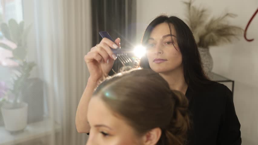 Makeup artist styling a young woman during a beauty preparation