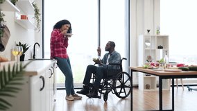 A diverse couple enjoys a healthy meal in their bright, modern kitchen. One person is in a wheelchair. - Powered by Shutterstock - Get 15% off with code: PIKWIZARD15