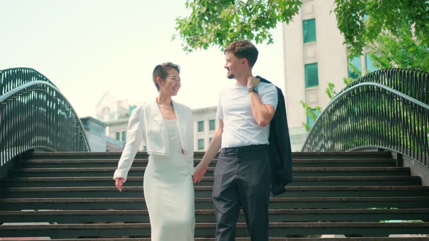 Couple walking down urban stairs in wedding outfits