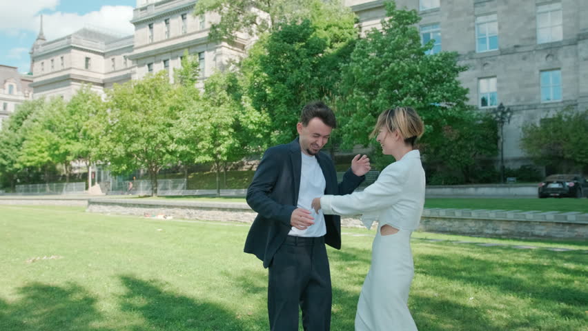 Couple popping champagne and celebrating in park