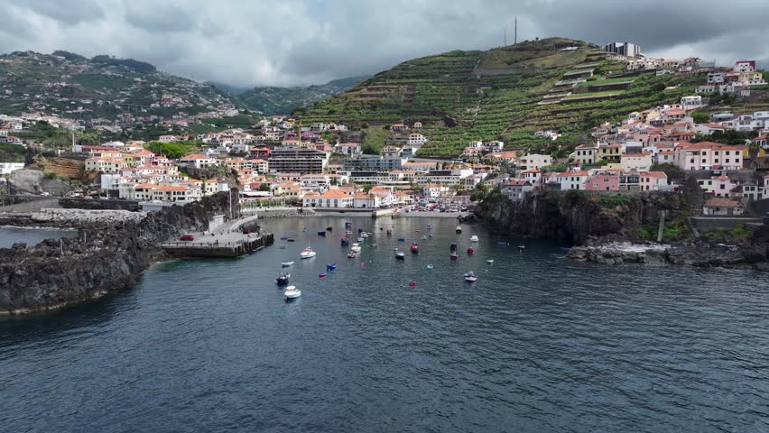 Aerial dolly over local fishing boats in harbor of Câmara de Lobos on Madeira