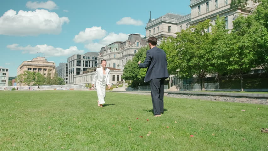 Barefoot couple dancing on grass near historic buildings