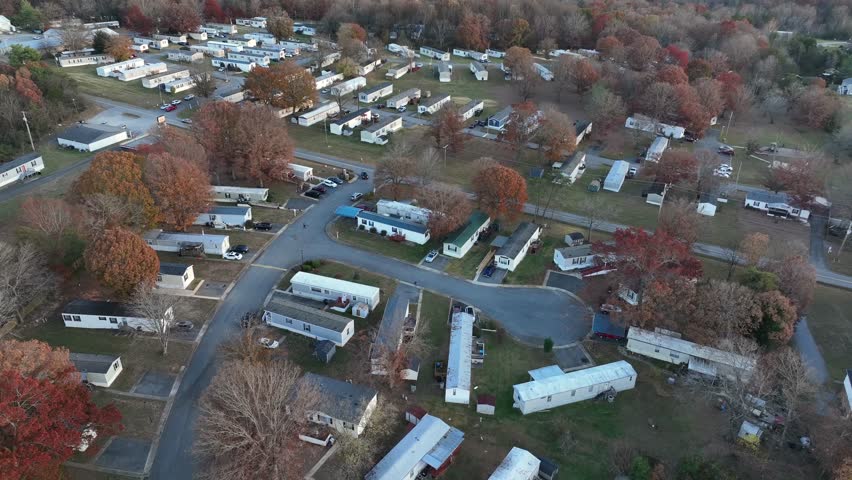 Peaceful low income housing with mobile trailer homes in idyllic suburbia of American Town. Late autumn with colored trees at sunset. Aerial view. Virginia, usa