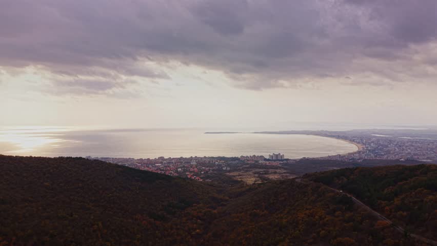 This stunning aerial view captures the coastline near Varna, Bulgaria, showcasing the tranquil waters and cityscape as the sun sets behind the horizon.