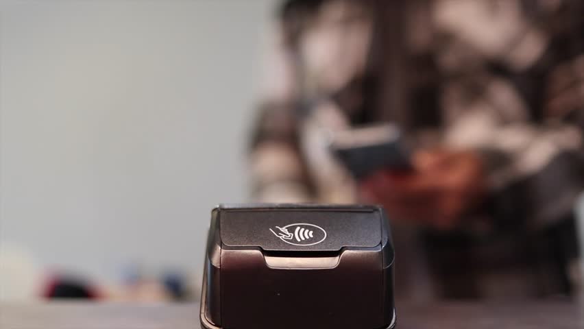 Customer paying with a smartphone using nfc technology on a credit card terminal