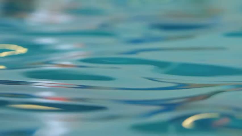 Close up slow motion shot of water surface ripples with sunlight reflection background
