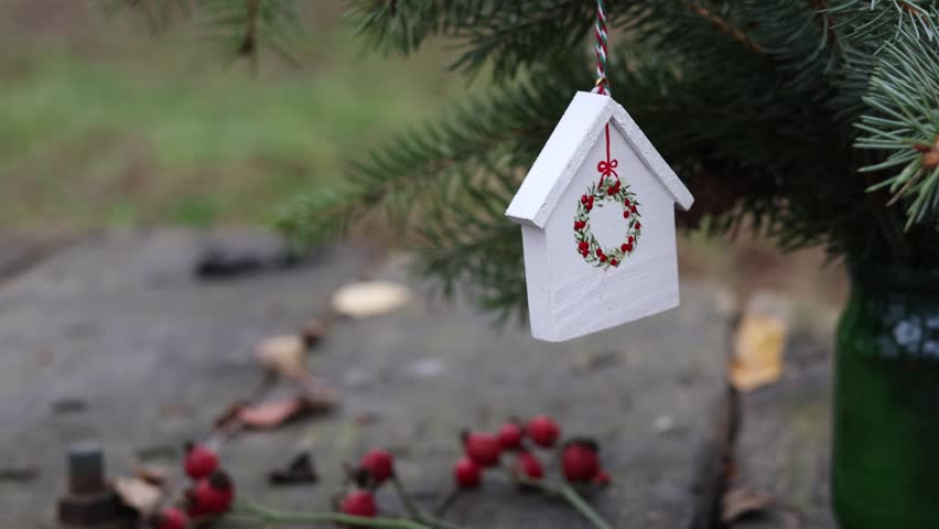 Close-up of a Christmas tree branch decorated with delightful, handmade wooden house ornaments, radiating a festive and nostalgic holiday spirit in an outdoor setting, spreading magic and joy.
