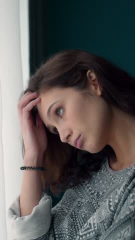 A woman looks out the window lost in thought during daylight hours