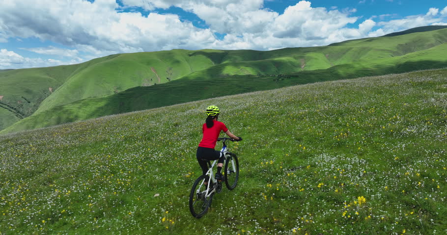 Riding mountain bike in the beautiful flowering grassland and forest mountains