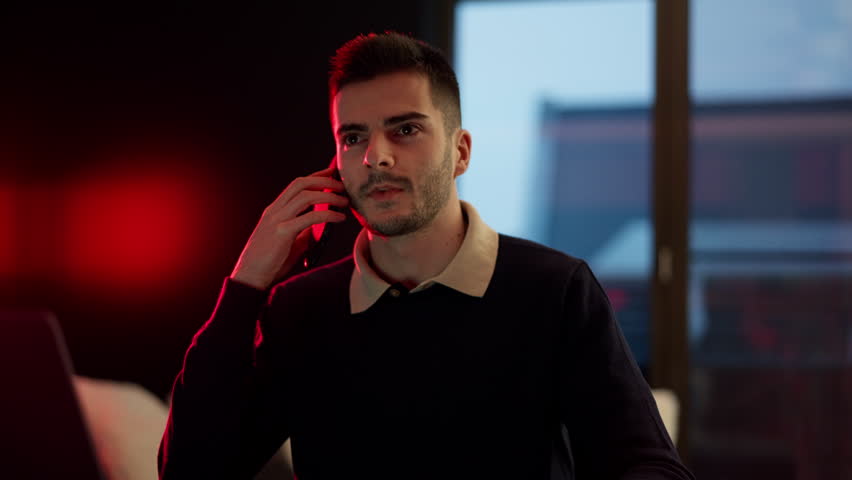 A person talking on the phone with a positive, nice tone in a modern office or studio setting. Light, upbeat mood, friendly discussion, and a productive work atmosphere.