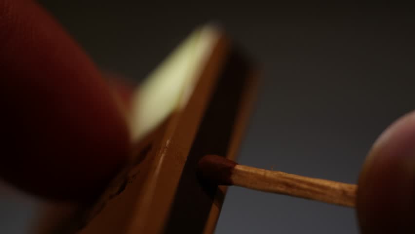 An extreme macro video of a bursting match captured in ultra-close detail. The mesmerizing physics of ignition, the flash of the spark, the rapid consumption of the chemical tip, and the birth of a da