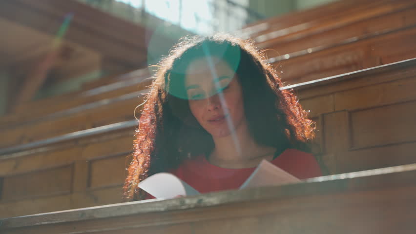 Hispanic student girl turning pages in textbook study in university auditorium woman start learning class lecture female at table writing studying write learn course in sunny sunbeam college education