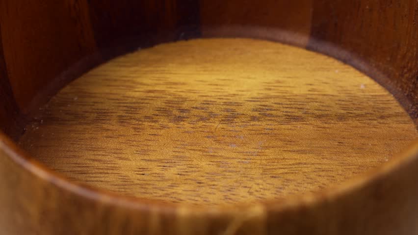 Many colorful fruit jelly beans falling down into the wooden bowl close up
