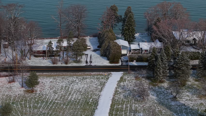 Aerial view of lakeside homes and snowy yards along Lake Ontario in New York State after the first winter snowfall. High quality 4k footage