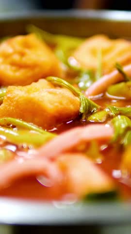 Close-up of authentic Thai pink noodle soup or Yen Ta Fo featuring fried tofu and morning glory in a hot pot for delicious cuisine content