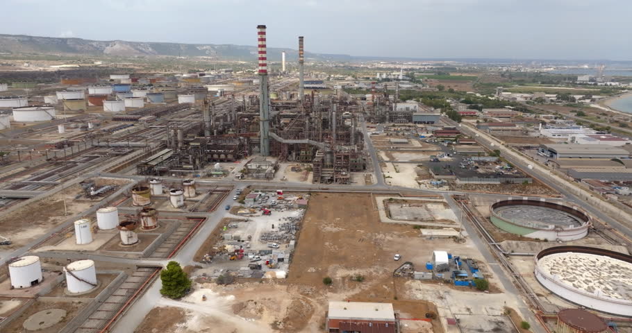 Aerial view of a large, complex oil and chemical refinery. It is located in the industrial area of Priolo, situated between Syracuse and Augusta, in Sicily, Italy. The Mediterranean Sea is at horizon.