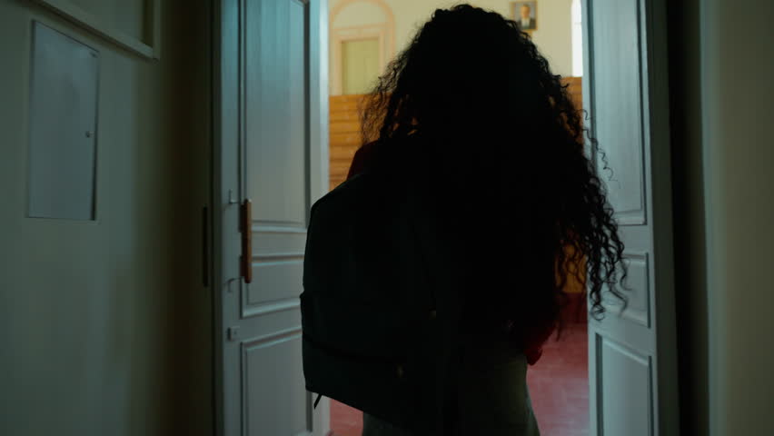 Hispanic student girl entering university auditorium looking around surprised back view Latina woman Caucasian female lady go amazed wonder come in walking in class college academy indoors studying