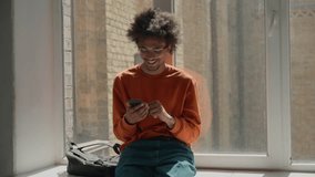 African American student guy using mobile phone smiling in university corridor happy man relaxing near window college school smartphone app chatting positive education study break male use cellphone - Powered by Shutterstock - Get 15% off with code: PIKWIZARD15