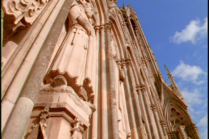  Exterior shot of Cathedral Notre Dame de Reims in Reims, France; MS side-long view of tower wall, camera tilts down to edge of tower with a high angle view of the city in background.