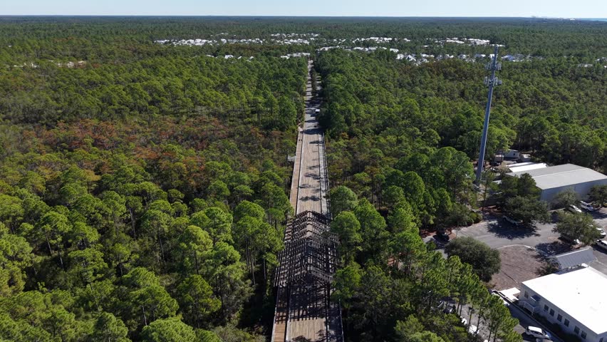 Sandgrass Boulevard long straight road cutting through dense green forest to a small settlement from above, Santa Rosa Beach, Florida, USA