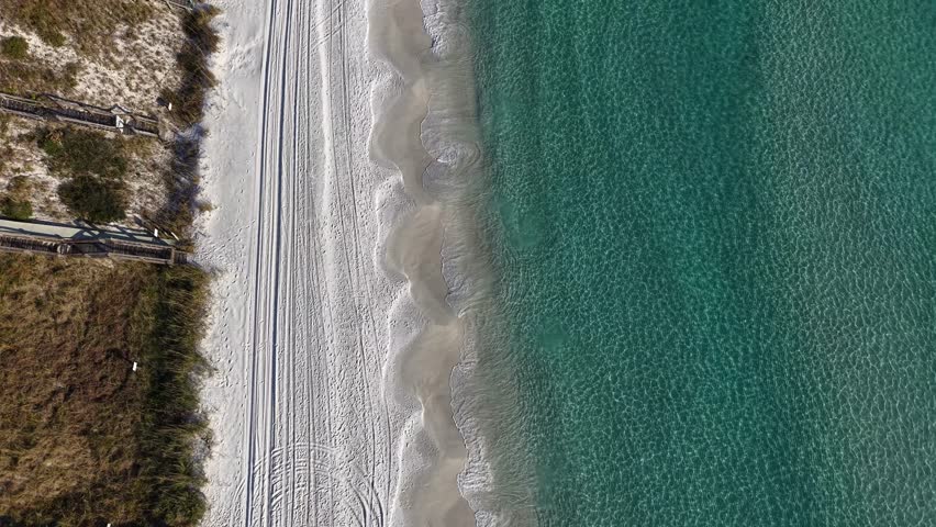 Top-down aerial fly over Seagrove Beach shoreline where white sand meets crystal clear Gulf of Mexico, Florida, USA