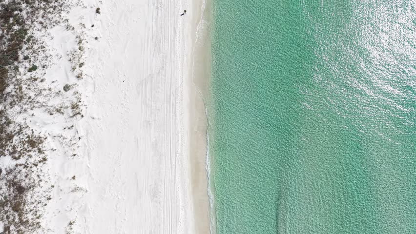 Top-down drone fly along white sandy beach with shallow crystal clear Gulf of Mexico shoreline, Panama City Beach, Florida, USA