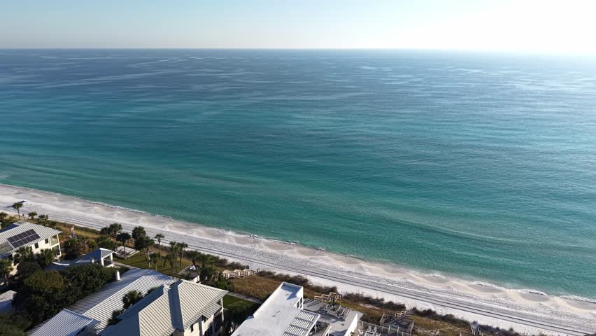 Panoramic drone fly over long coastline of Seagrove Beach with gentle waves and white sandy beach, Florida, USA