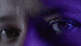 Detailed close-up shot of eyes illuminated by purple lighting. Captures texture and emotion with intriguing gaze and shadow play. Artistic focus on expression and mood in intimate setting. - Powered by Shutterstock - Get 15% off with code: PIKWIZARD15