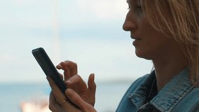 Young woman's silhouette typing on her smartphone while standing outdoors with a blurred seascape in the background, enjoying a beautiful sunset and connecting with friends online - Powered by Shutterstock - Get 15% off with code: PIKWIZARD15