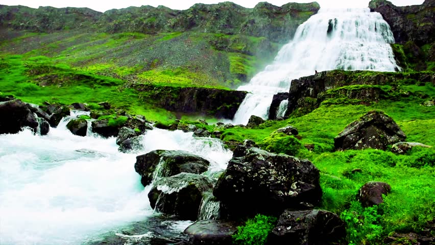 Dynjandi waterfall in Iceland, cascading in multiple tiers, surrounded by lush nature and rugged cliffs, showcasing the majestic beauty of Icelandic wilderness.