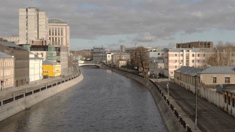 Drone Flying Forward Over Narrow Urban River in Spring