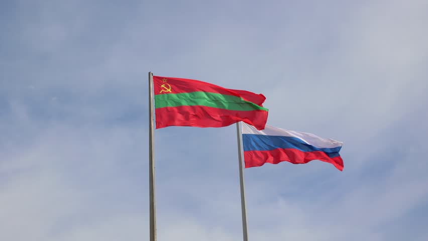 National flags of the breakaway state of Transnistria and the Russian Federation waving proudly together against a blue sky, symbolizing the strong relationship and political alliance between them
