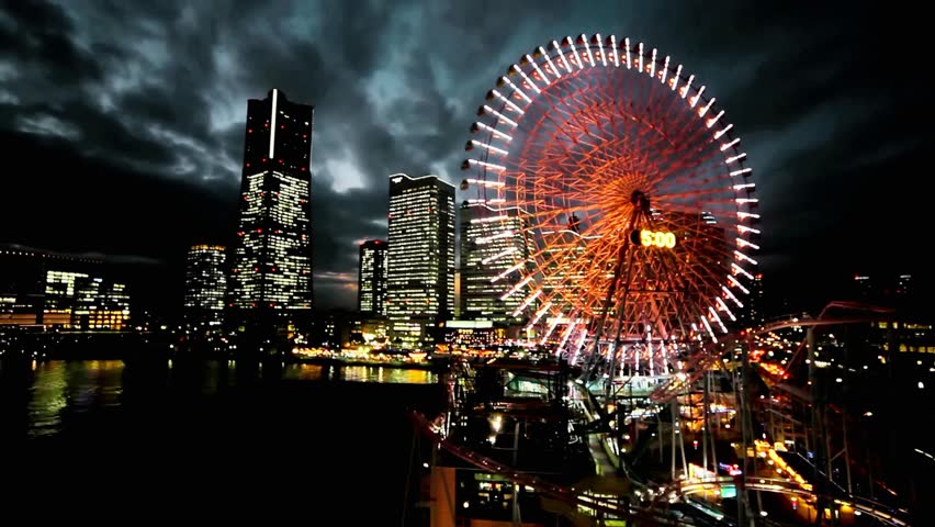 Night aerial view of Yokohama, Japan, showcasing illuminated city streets, skyscrapers, waterfront, and vibrant urban lights against a dark sky.