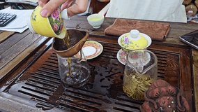 A traditional Chinese tea ceremony with hot water poured into a cup, displaying loose leaves, porcelain teaware and a wooden tea table during the gentle brewing process. - Powered by Shutterstock - Get 15% off with code: PIKWIZARD15