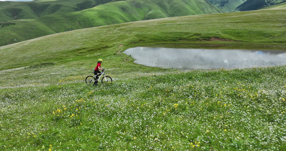 Riding mountain bike in the beautiful flowering grassland and forest mountains
