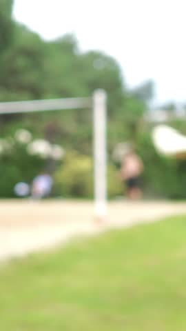 Blurred image of unidentified pals engaged in a beach volleyball game on a sandy court. Enjoying a sunny day participating in outdoor summer sports