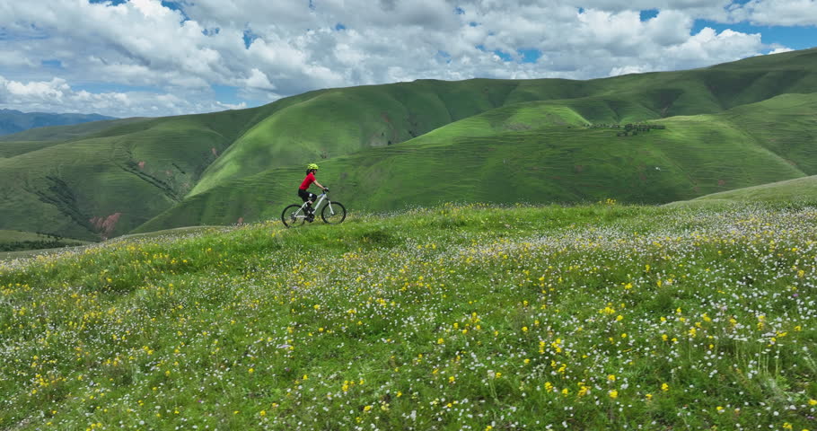 Riding mountain bike in the beautiful flowering grassland and forest mountains