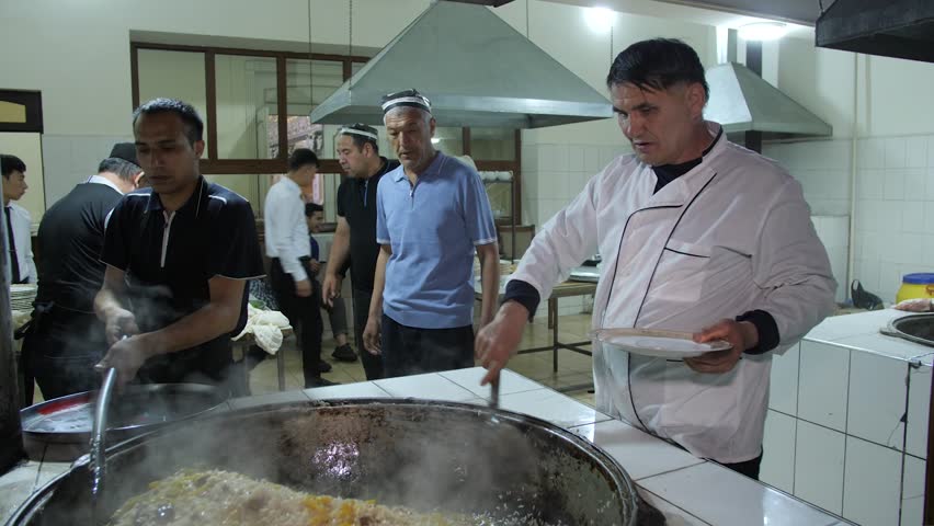 15 October 2025, Fergana, Uzbekistan – A chef serving hot food into china plates and large serving dishes during a local cooking demonstration.