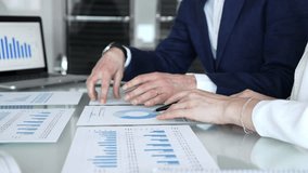 Business professionals collaborating in a modern office, reviewing financial reports, charts and a laptop on a glass table while discussing data analytics, strategy and planning - Powered by Shutterstock - Get 15% off with code: PIKWIZARD15