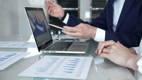 Business professionals collaborating in a modern office, reviewing financial reports, charts and a laptop on a glass table while discussing data analytics, strategy and planning - Powered by Shutterstock - Get 15% off with code: PIKWIZARD15