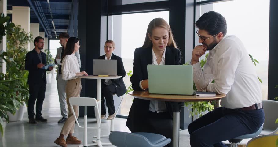 Group of business professionals in office working together in small groups. Men and women discussing projects, exchanging ideas, collaborating during productive team meeting to solve work issues.