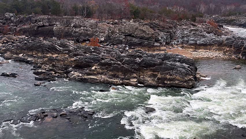 rocky river landscape with fast flowing water surrounded by rugged cliffs and muted autumn forest colors