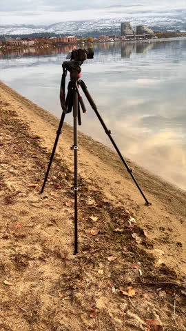 Vertical format of a high-end camera on a tripod placed at the water