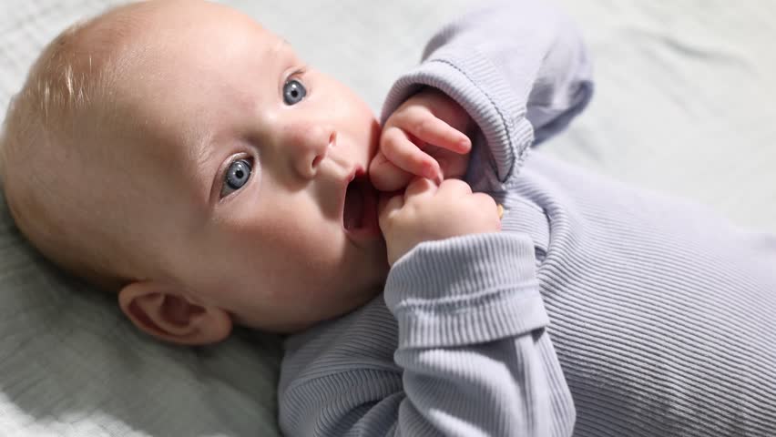 Cute newborn baby lying on bed, above view. Camera moving in